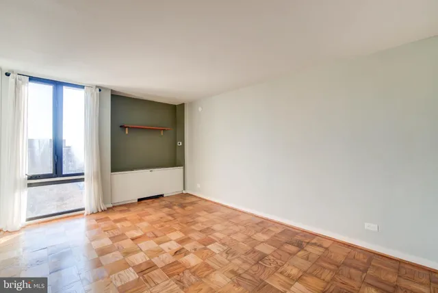 a view of an empty room with wooden floor and a window
