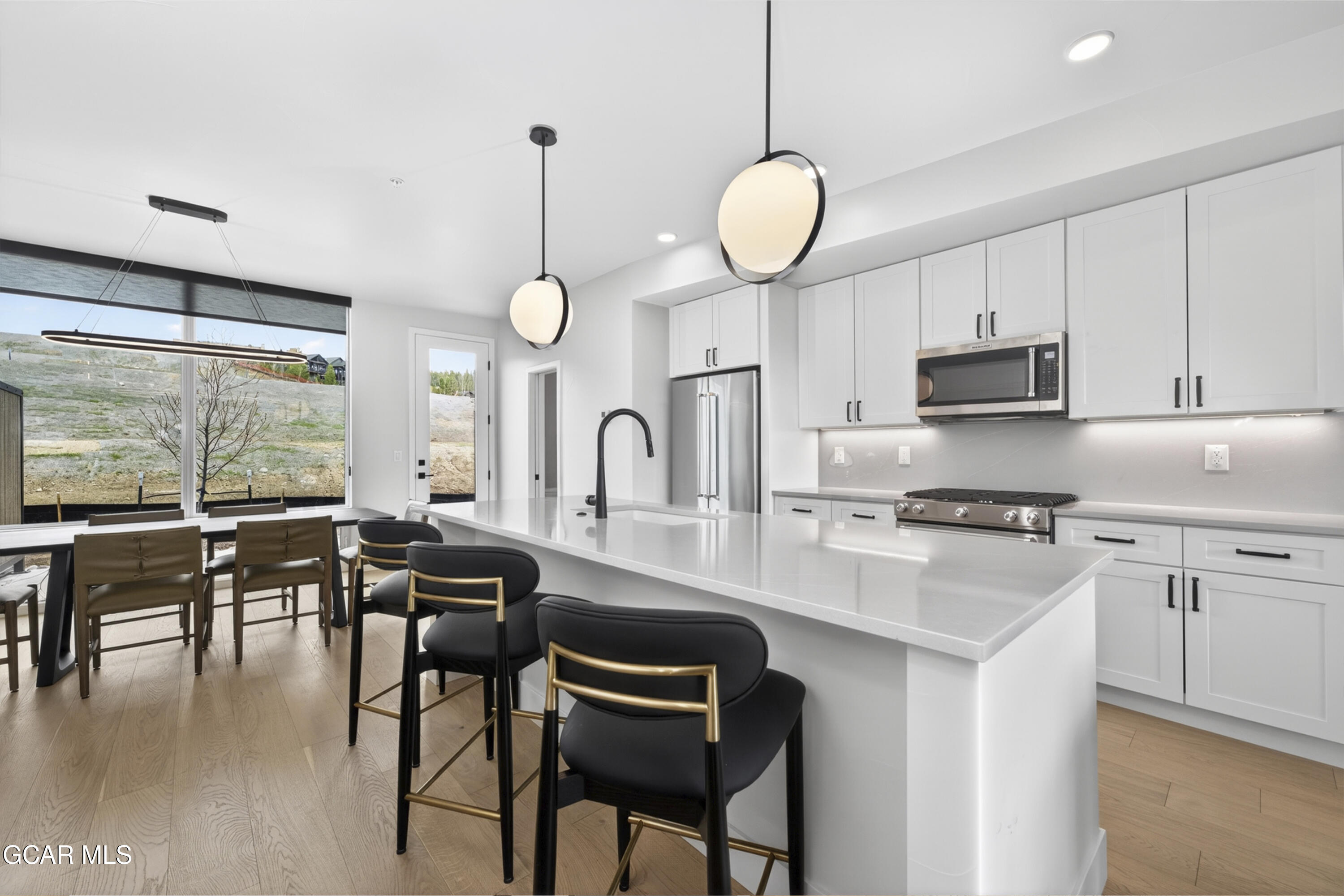 56 Wheeler Road Winter Park, CO 80482 - Photo 7 of 42 a kitchen with stainless steel appliances granite countertop a stove a sink a microwave a dining table and chairs with wooden floor