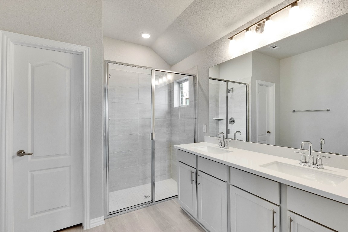 13709 Tucker Hedge Pass Elgin, TX 78621 - Photo 7 of 14 Bathroom with a shower stall, double vanity, and lofted ceiling