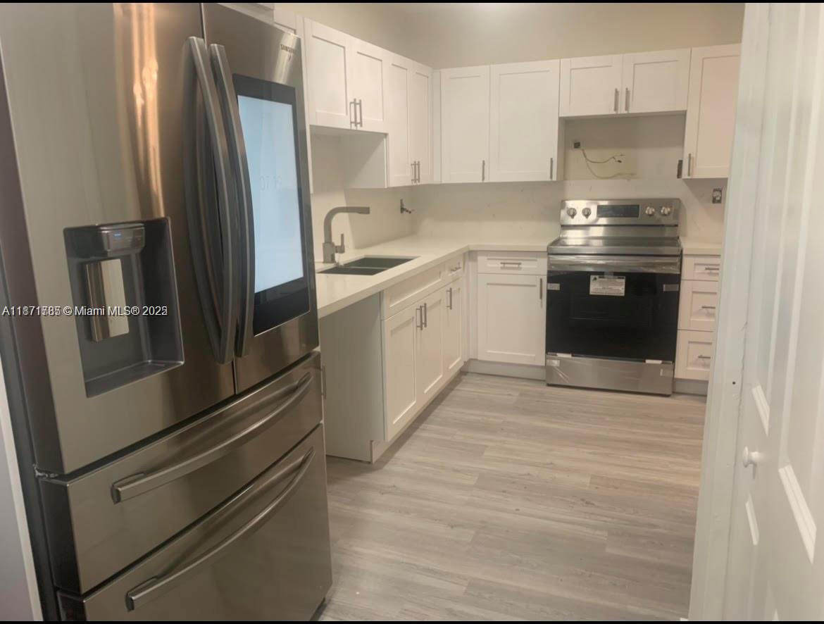 6765 Southwest 17th Street, Unit 6765 Miami, FL 33155 - Photo 2 of 9 a kitchen with stainless steel appliances a refrigerator stove and cabinets