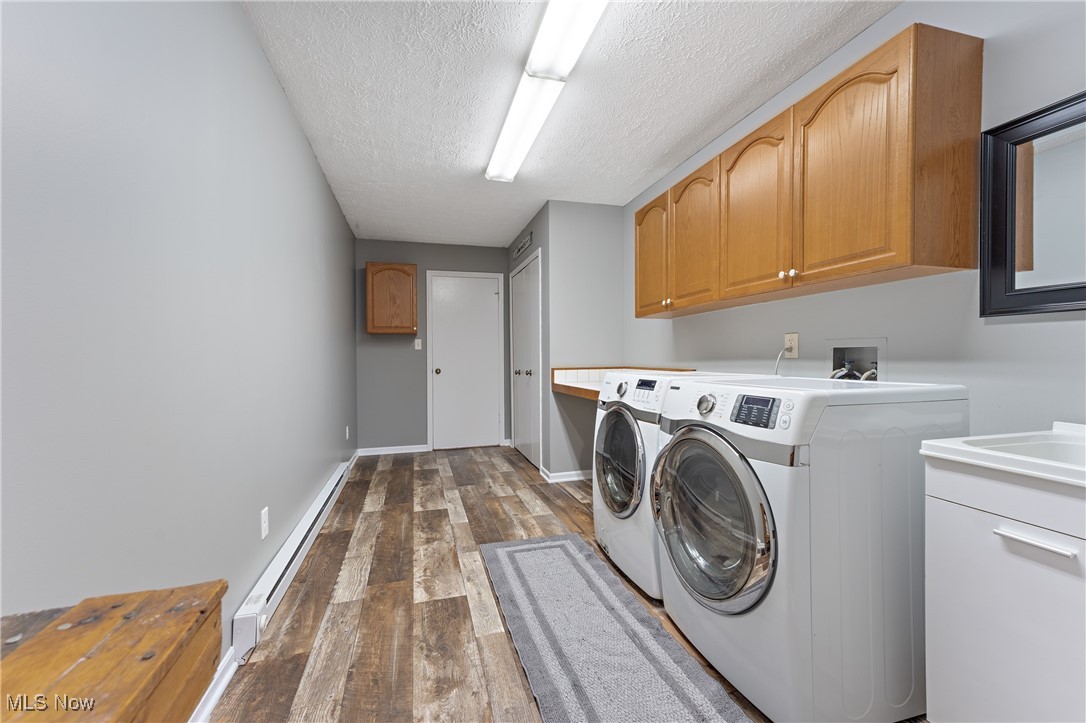 645 Killinger Road Clinton, OH 44216 - Photo 24 of 50 Washroom featuring a baseboard radiator, cabinets, dark hardwood / wood-style floors, a textured ceiling, and washer and dryer