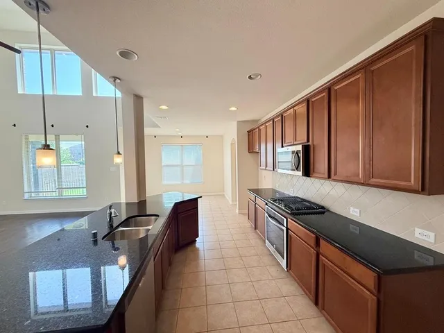 a large kitchen with granite countertop lots of counter top space and stainless steel appliances