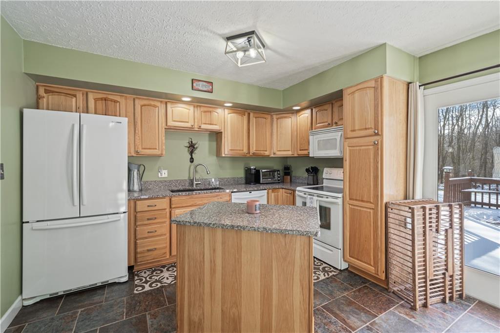 261 Casselman Road Markleton, PA 15551 - Photo 17 of 42 a kitchen with granite countertop a refrigerator a sink a stove and white cabinets