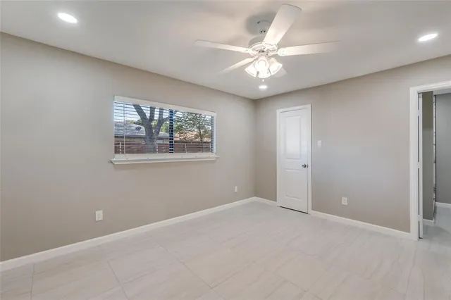 an empty room with windows and fan