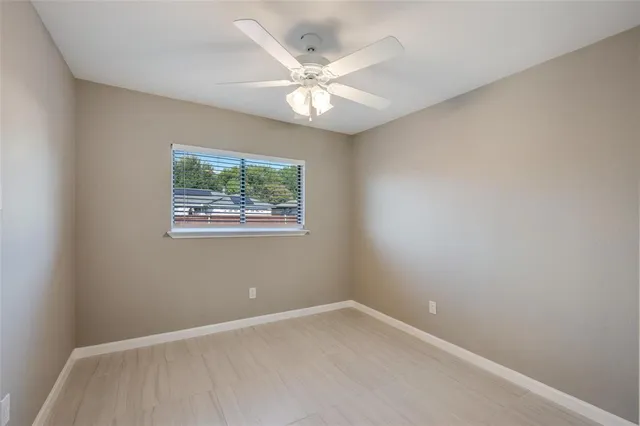 an empty room with a window and a fan