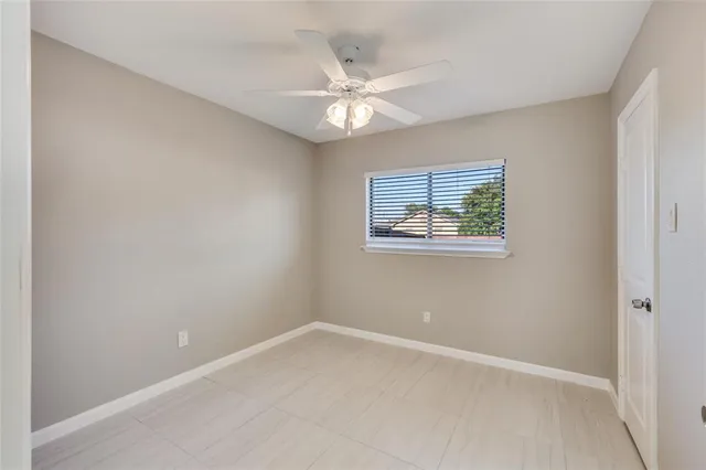 an empty room with a window and a ceiling fan