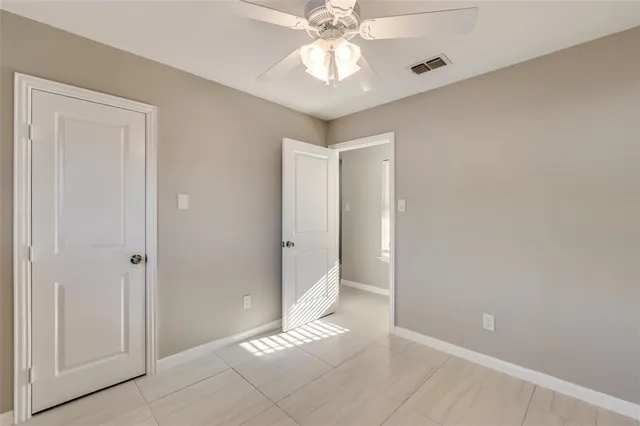 a view of an empty room and chandelier fan