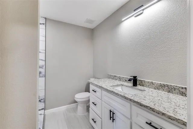 a bathroom with a granite countertop sink a toilet and a shower