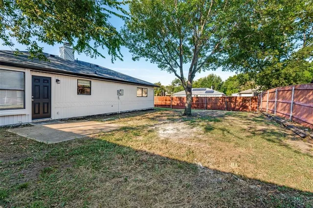 a view of a backyard with large tree and wooden fence