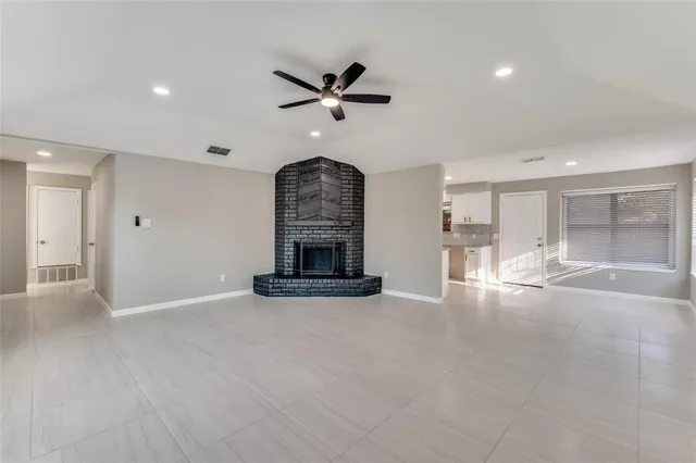 an empty room with wooden floor a ceiling fan and windows