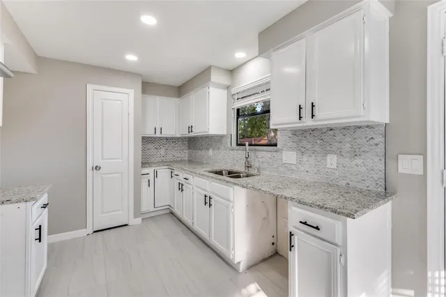 a kitchen that has a lot of white cabinets and stainless steel appliances