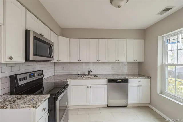 a kitchen with white cabinets and stainless steel appliances