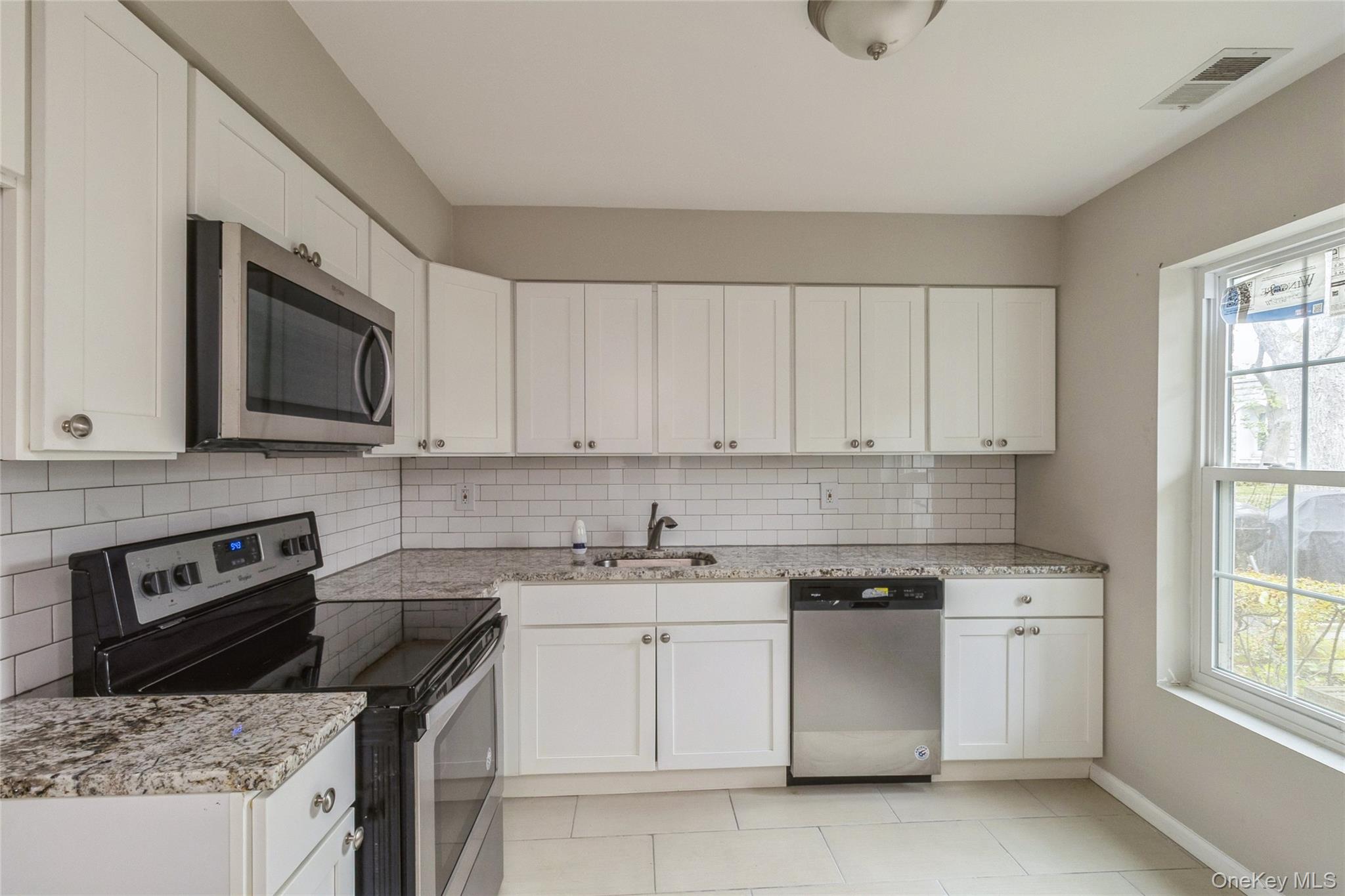 655 Middle Country Road, Unit 4D1 Coram, NY 11727 - Photo 13 of 27 a kitchen with white cabinets stainless steel appliances and sink