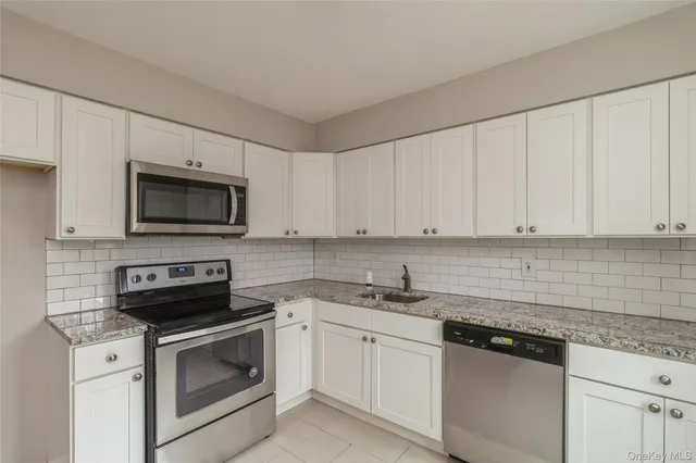 a kitchen with white cabinets appliances and sink