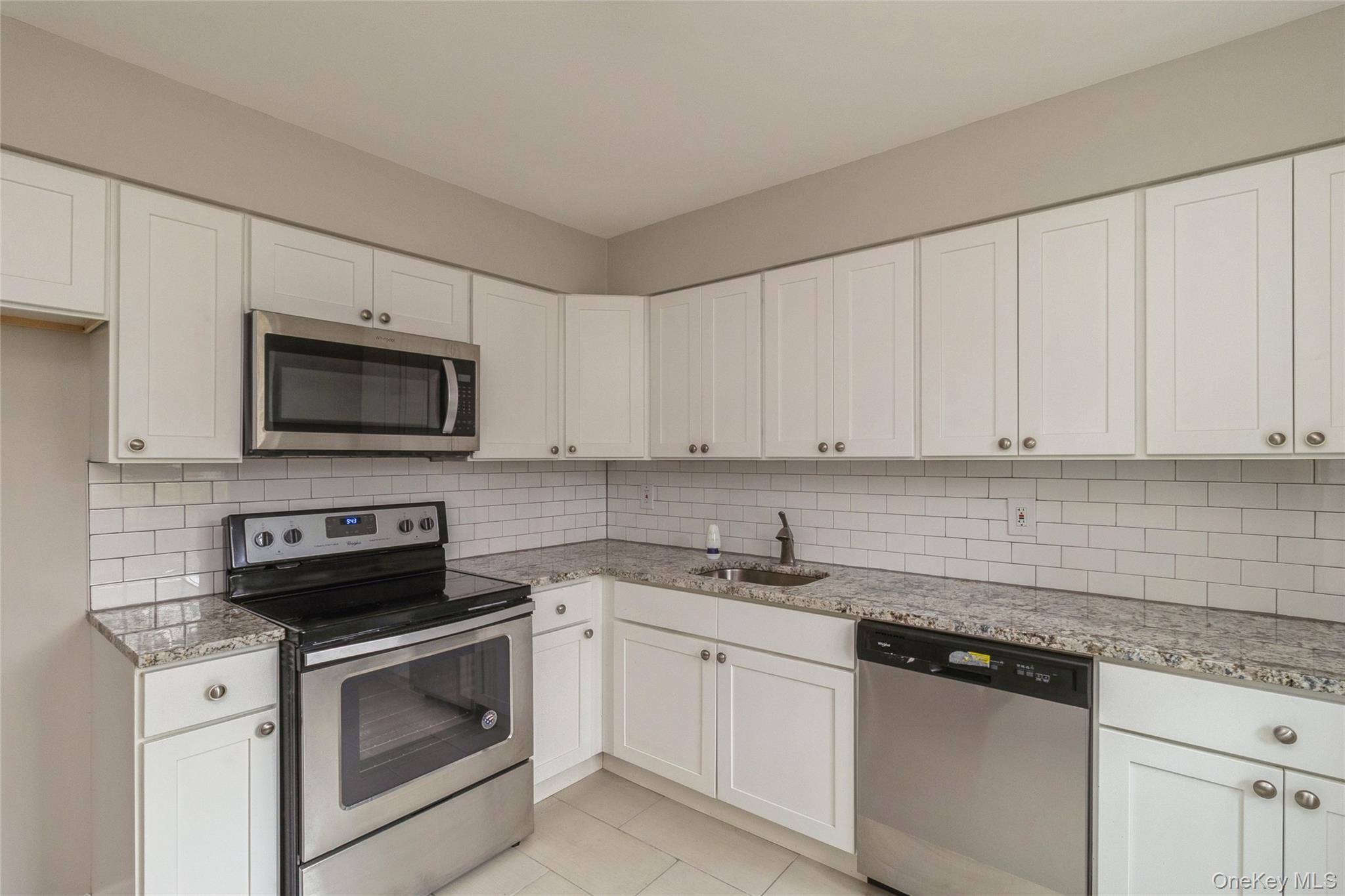 655 Middle Country Road, Unit 4D1 Coram, NY 11727 - Photo 14 of 27 a kitchen with white cabinets and stainless steel appliances