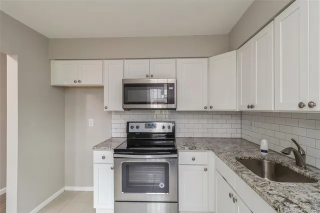 a kitchen with granite countertop white cabinets and white appliances