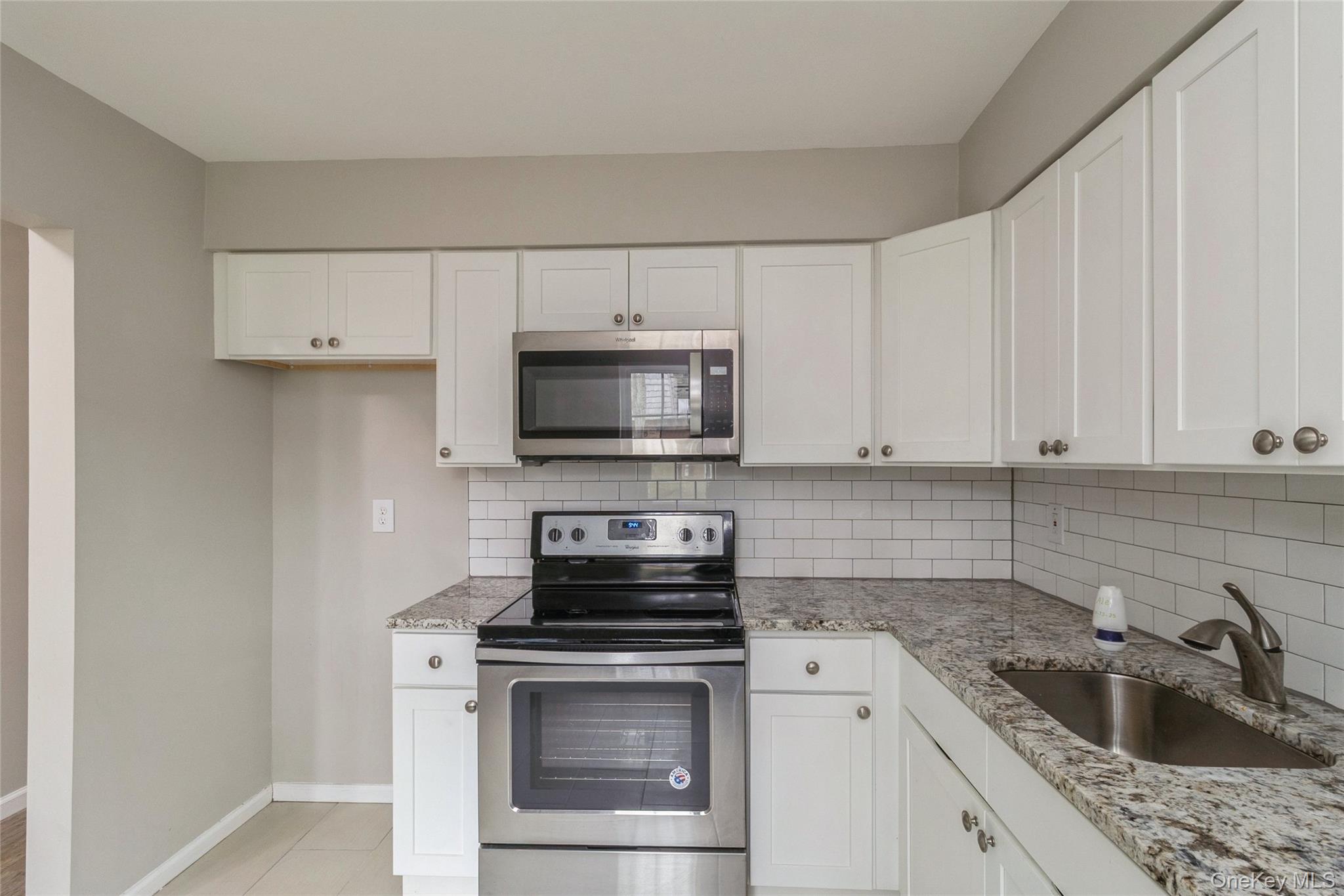 655 Middle Country Road, Unit 4D1 Coram, NY 11727 - Photo 15 of 27 a kitchen with white cabinets appliances and sink