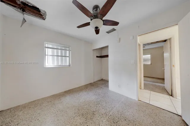 an empty room with a window and a ceiling fan