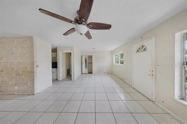a view of an empty room and chandelier fan