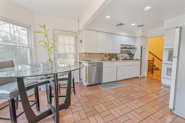 a kitchen with stainless steel appliances granite countertop a stove a sink a dining table and chairs