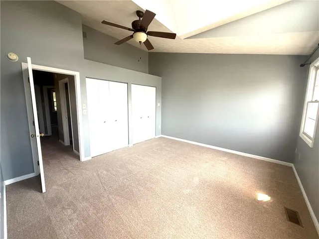 an empty room with windows and fan