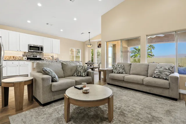 a living room with furniture a rug kitchen view and a window