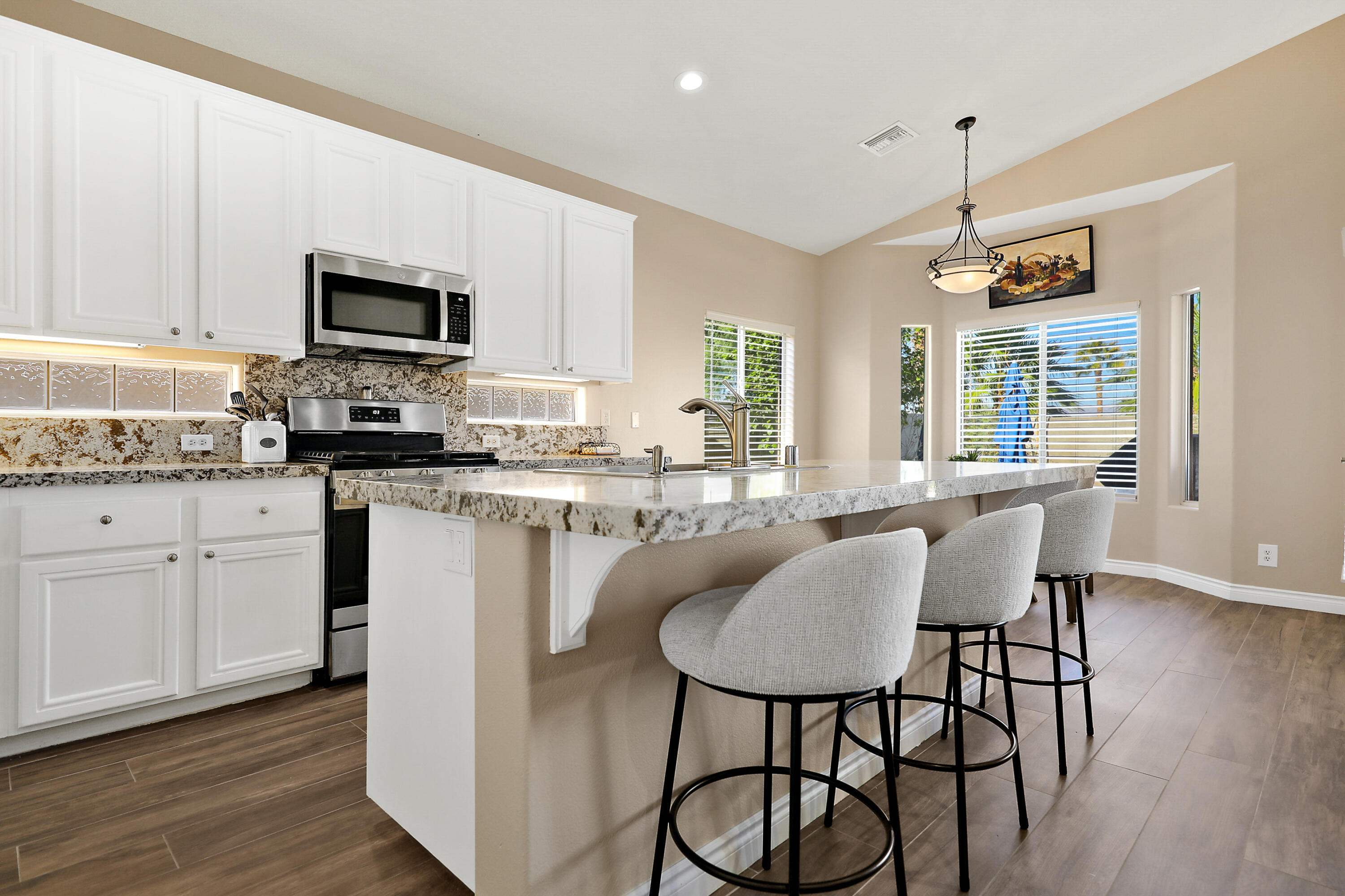 79948 Bethpage Avenue Indio, CA 92201 - Photo 10 of 30 a kitchen with stainless steel appliances granite countertop a stove a sink a microwave a dining table and chairs