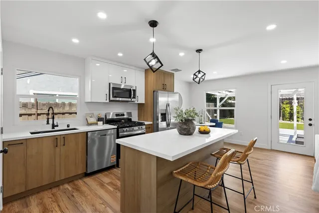 a kitchen with a dining table chairs stainless steel appliances and cabinets