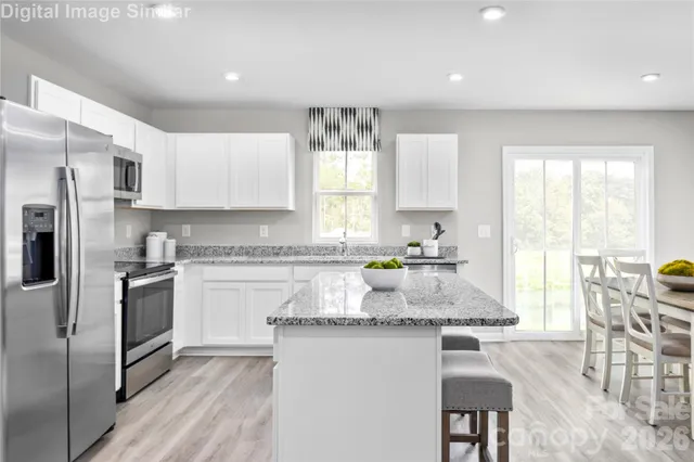 a kitchen with granite countertop a stove a sink a refrigerator a dining table and chairs