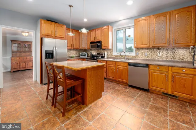 a kitchen with stainless steel appliances granite countertop a stove top oven a sink dishwasher a dining table and chairs with wooden floor