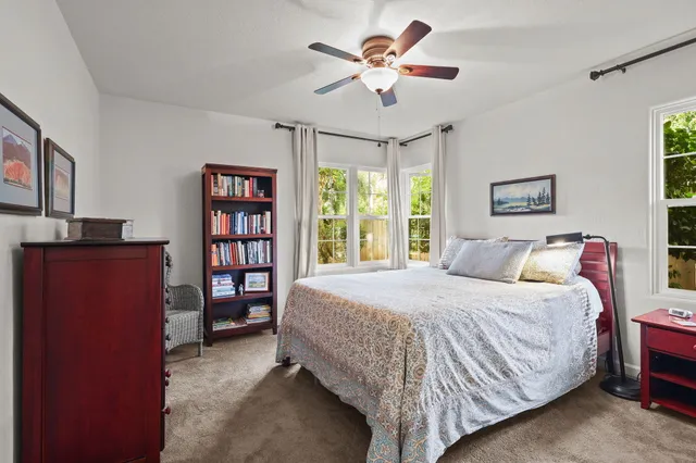 a bedroom with a bed a book shelf and a window