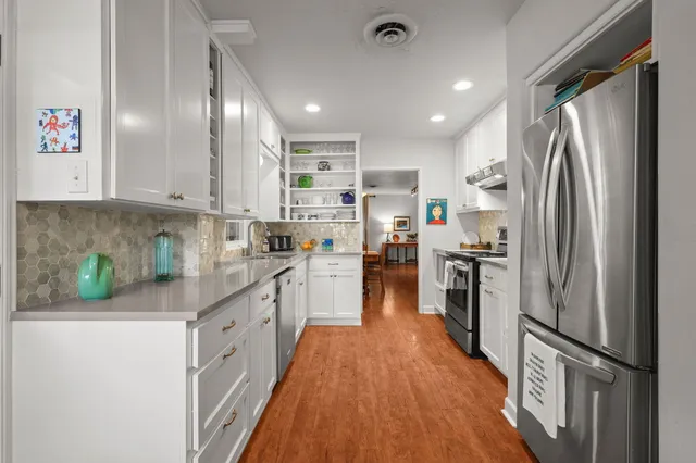a kitchen with stainless steel appliances a refrigerator sink and white cabinets