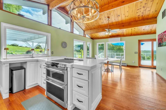 a kitchen with stainless steel appliances granite countertop a stove and a view of living room