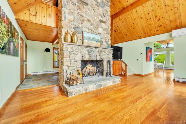 a view of a livingroom with fireplace a ceiling fan and wooden floor