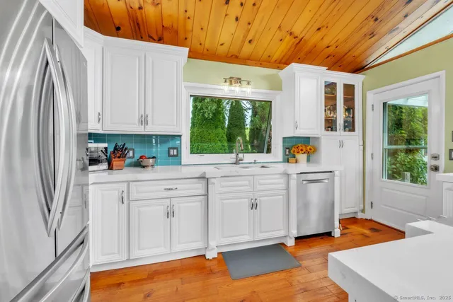 a kitchen with white cabinets and wooden floors