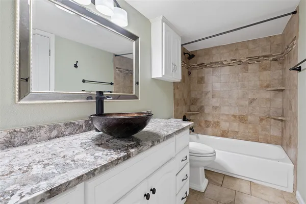 a bathroom with a granite countertop sink a toilet and bathtub
