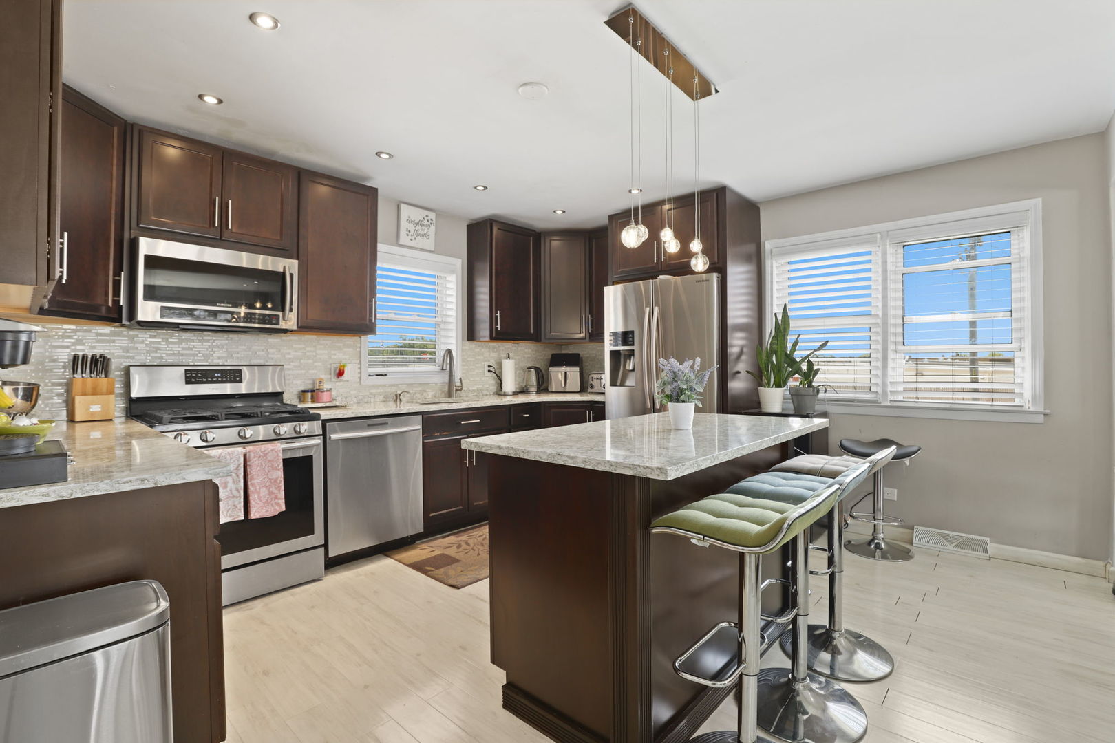 3939 Bobby Lane Schiller Park, IL 60176 - Photo 7 of 26 a kitchen with stainless steel appliances granite countertop a stove top oven a sink dishwasher a dining table and chairs with wooden floor