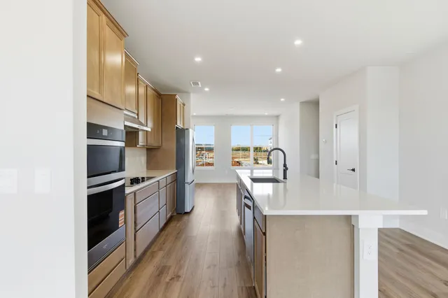 a kitchen with kitchen island a counter top space a sink stainless steel appliances and cabinets