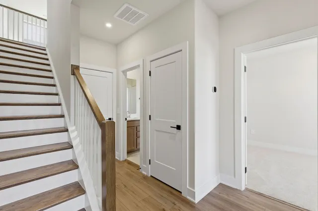 a view of a hallway with wooden floor and staircase