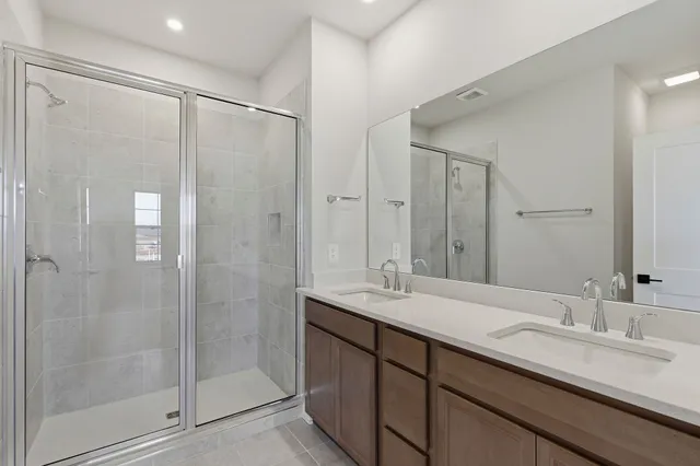 a bathroom with a double vanity sink mirror and shower