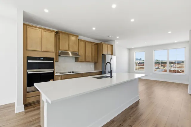 a kitchen with stainless steel appliances granite countertop a sink a stove and a refrigerator