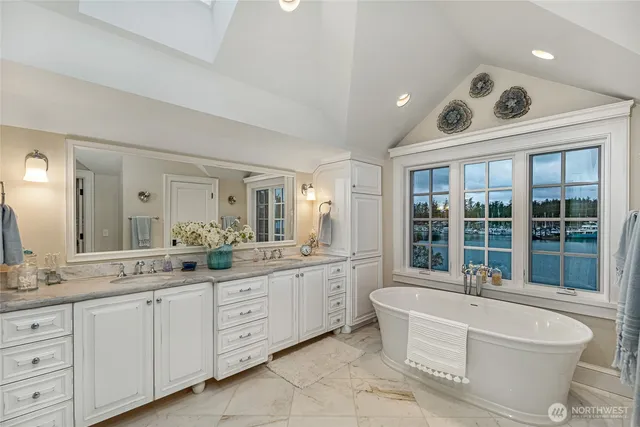 a large white bathroom with a large tub sink and mirror