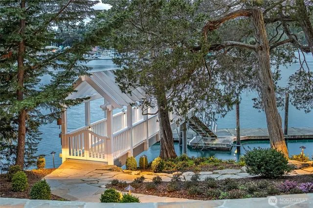 a view of a white house next to a road with large trees