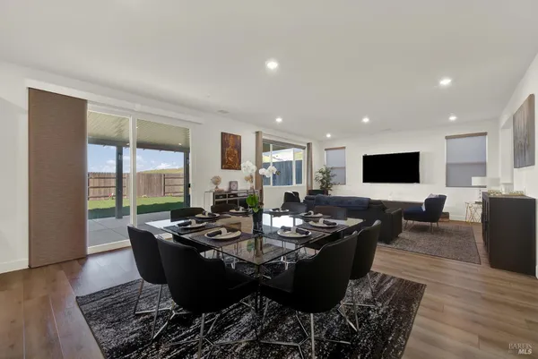 a kitchen with a dining table wooden floor and stainless steel appliances