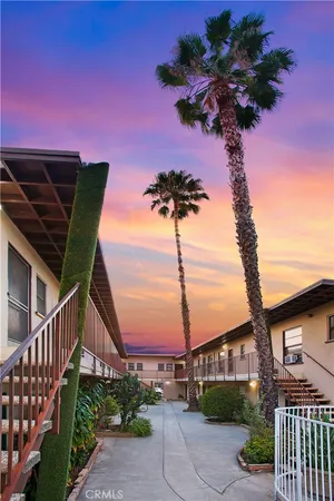 a vase of flowers sitting on a sidewalk with a small yard