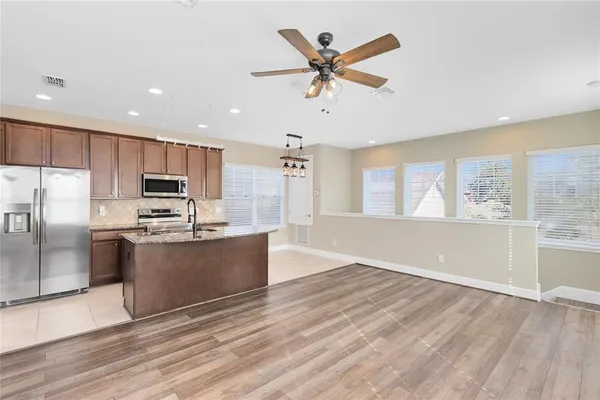 a large kitchen with stainless steel appliances wooden floor and a large window