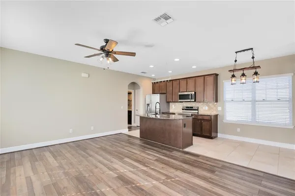a kitchen with stainless steel appliances kitchen island granite countertop a stove and a refrigerator with white cabinets