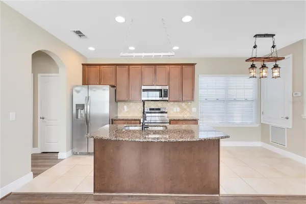 a kitchen with kitchen island a counter top space cabinets and stainless steel appliances
