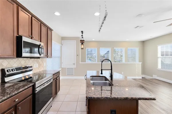 a kitchen with granite countertop a stove a sink and a microwave