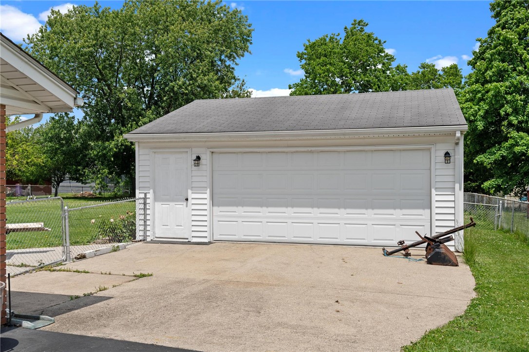 A spacious garage provides ample parking and storage, featuring a classic white door and durable asphalt roofing.